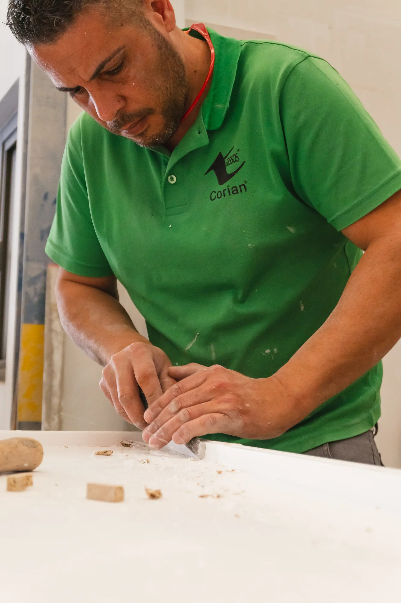 Trabajador repasando a mano el borde de una pieza blanca