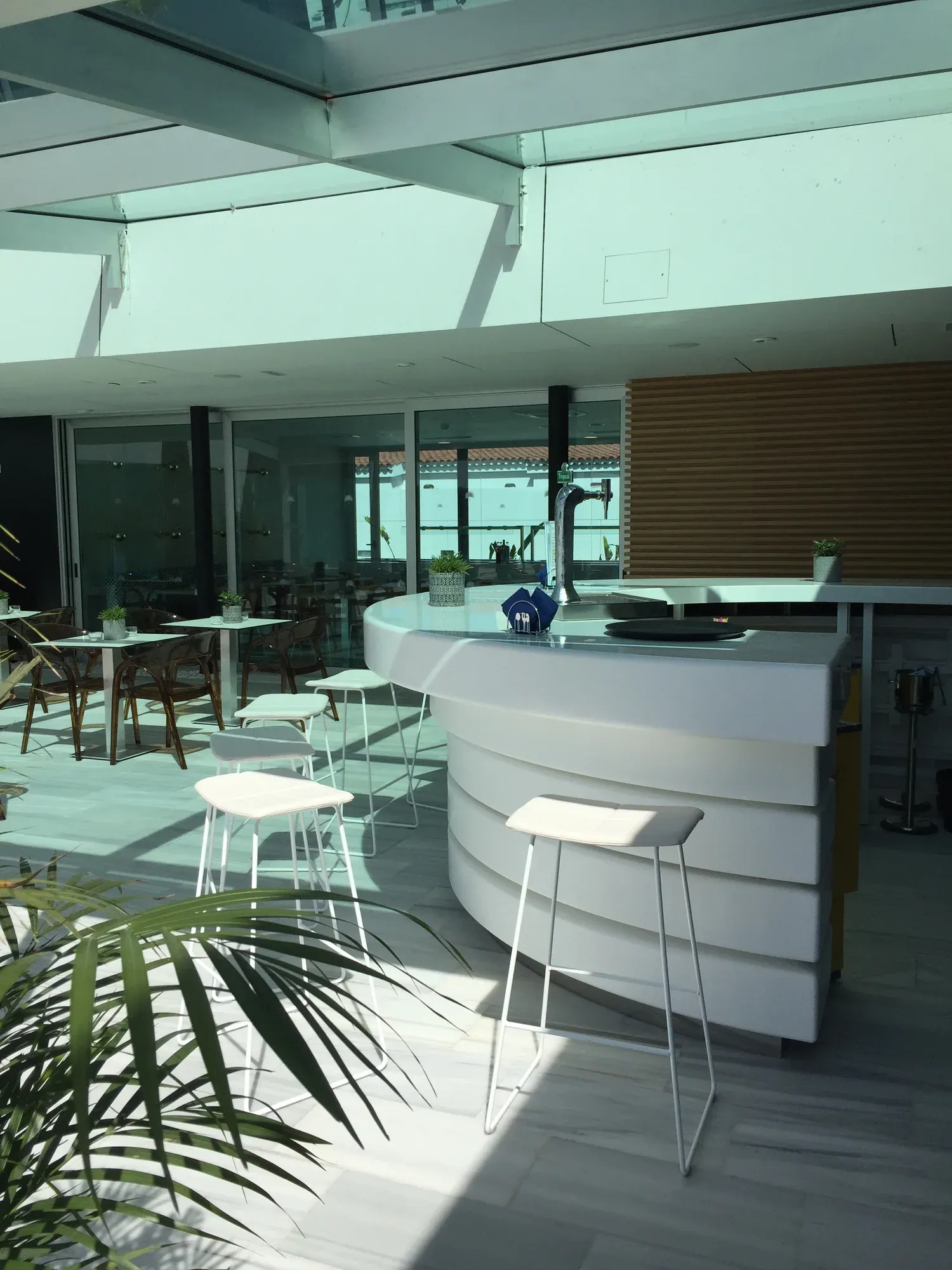 Barra blanca curva con taburetes en una terraza